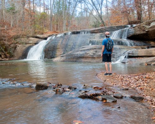 Hiker in front of waterfall at Mayo River State Park Fall Creek Falls